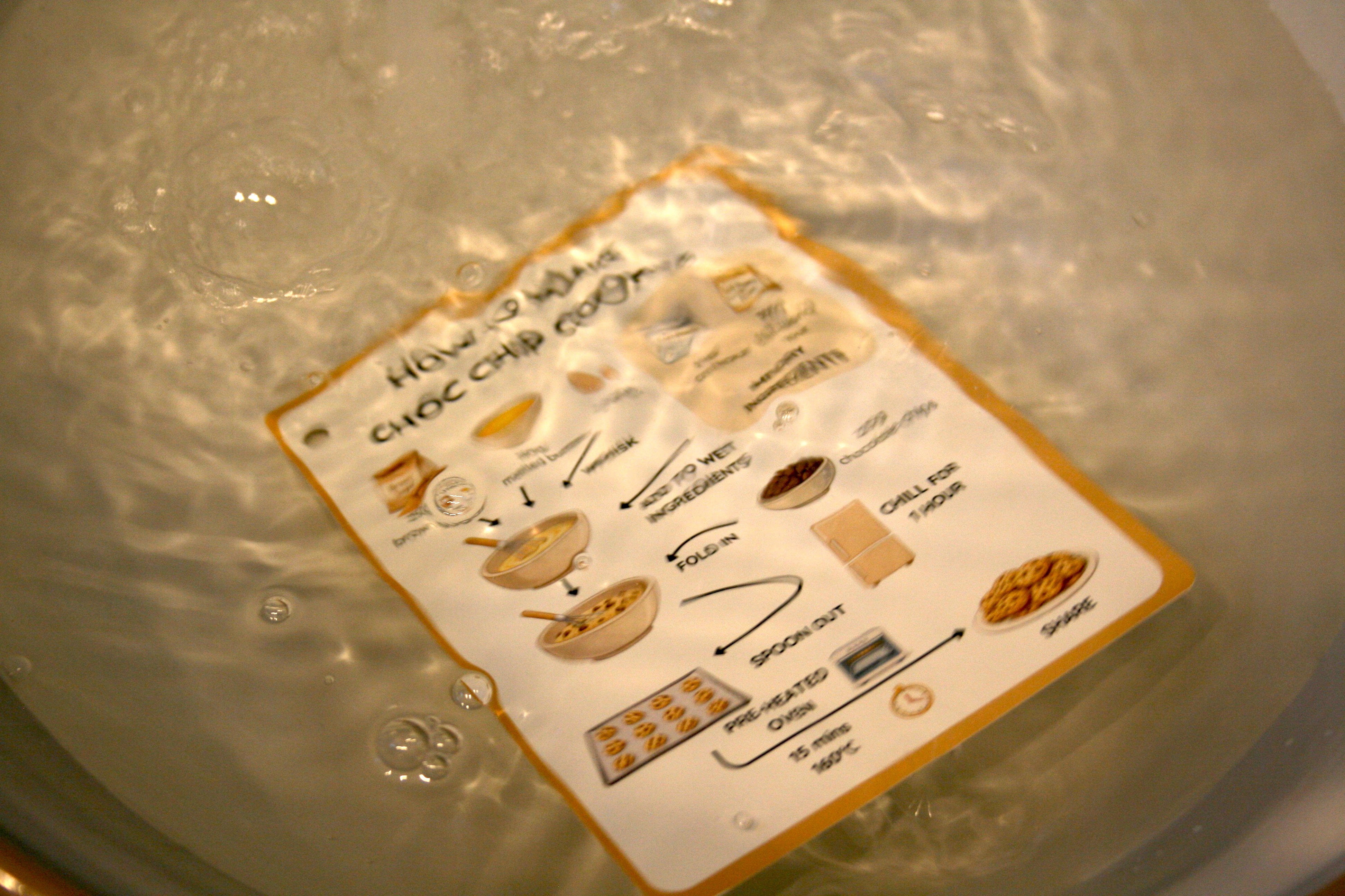 Waterproof ClearCook recipe card being wiped clean after cooking